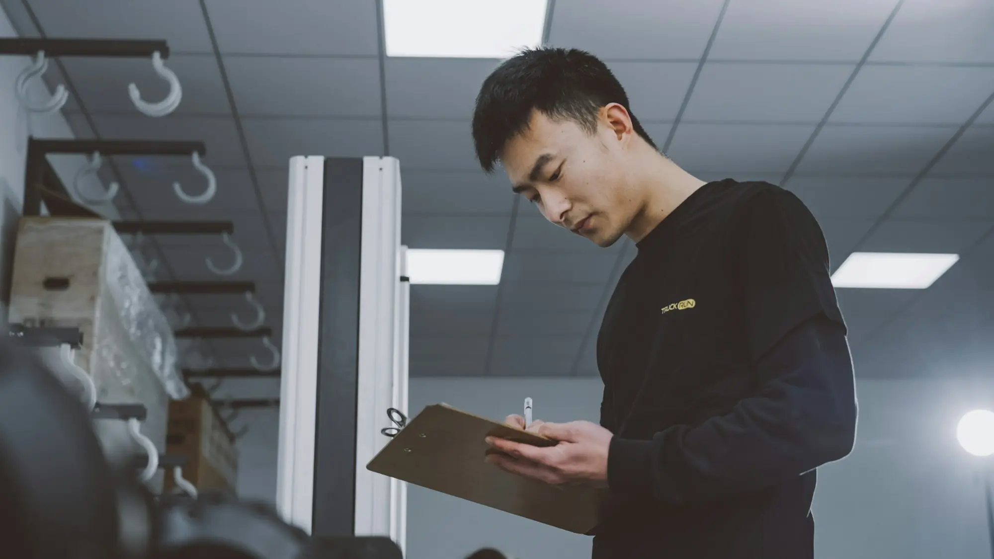 Mechanic checking a clipboard beside workshop equipment